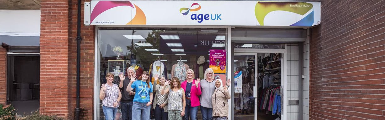 Age UK shop team waving outside the shop