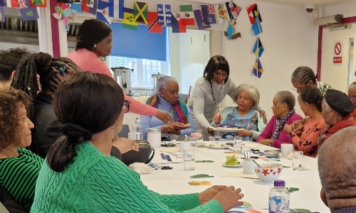 A group of older Caribbean men and women gathered around a table