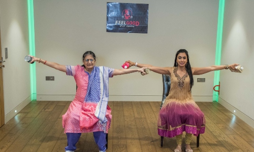A young South Asian woman and an older South Asian woman, sat doing exercises