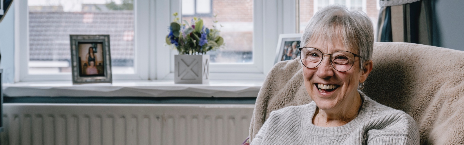 An older women with a silver pixie cut and glasses, laughing